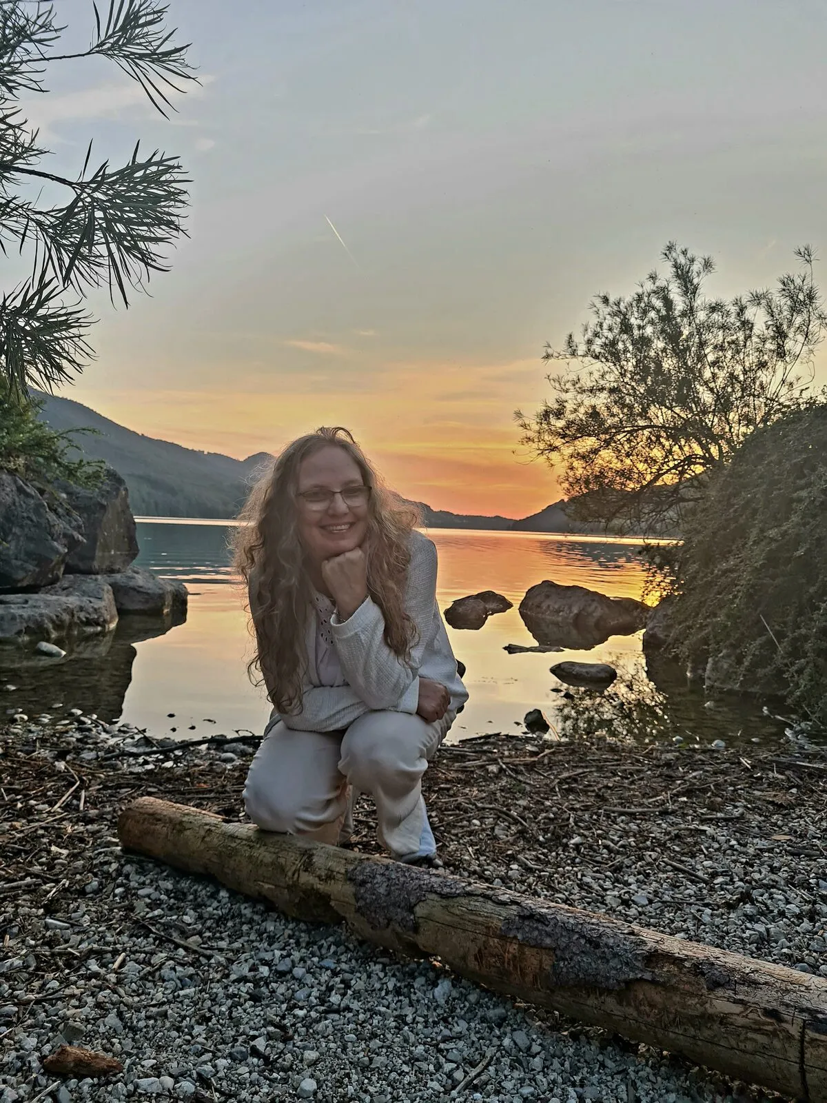 Antje Wäschle sitzt im Abendlicht am Seeufer und lächelt in die Kamera